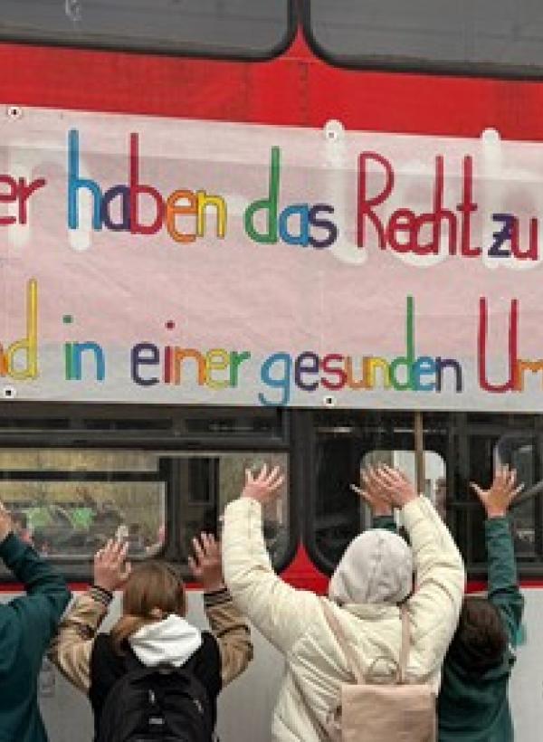 Kinder stehen vor Banner mit Aufschrift "Alle Kinder haben Rechte"